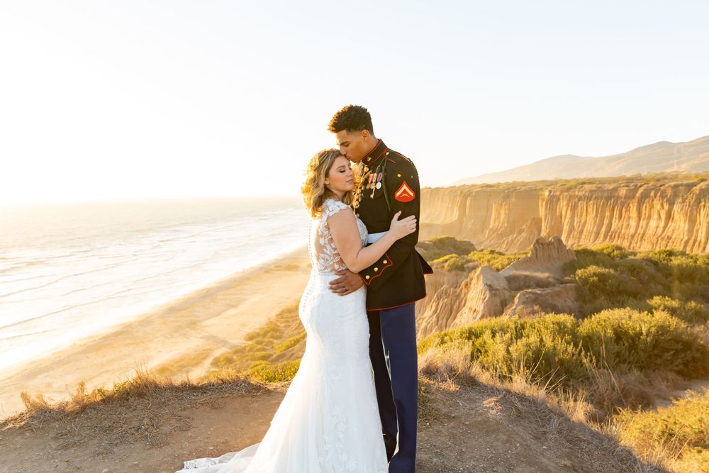 Wedding couple shares romantic moment on coastal cliffs during golden hour.