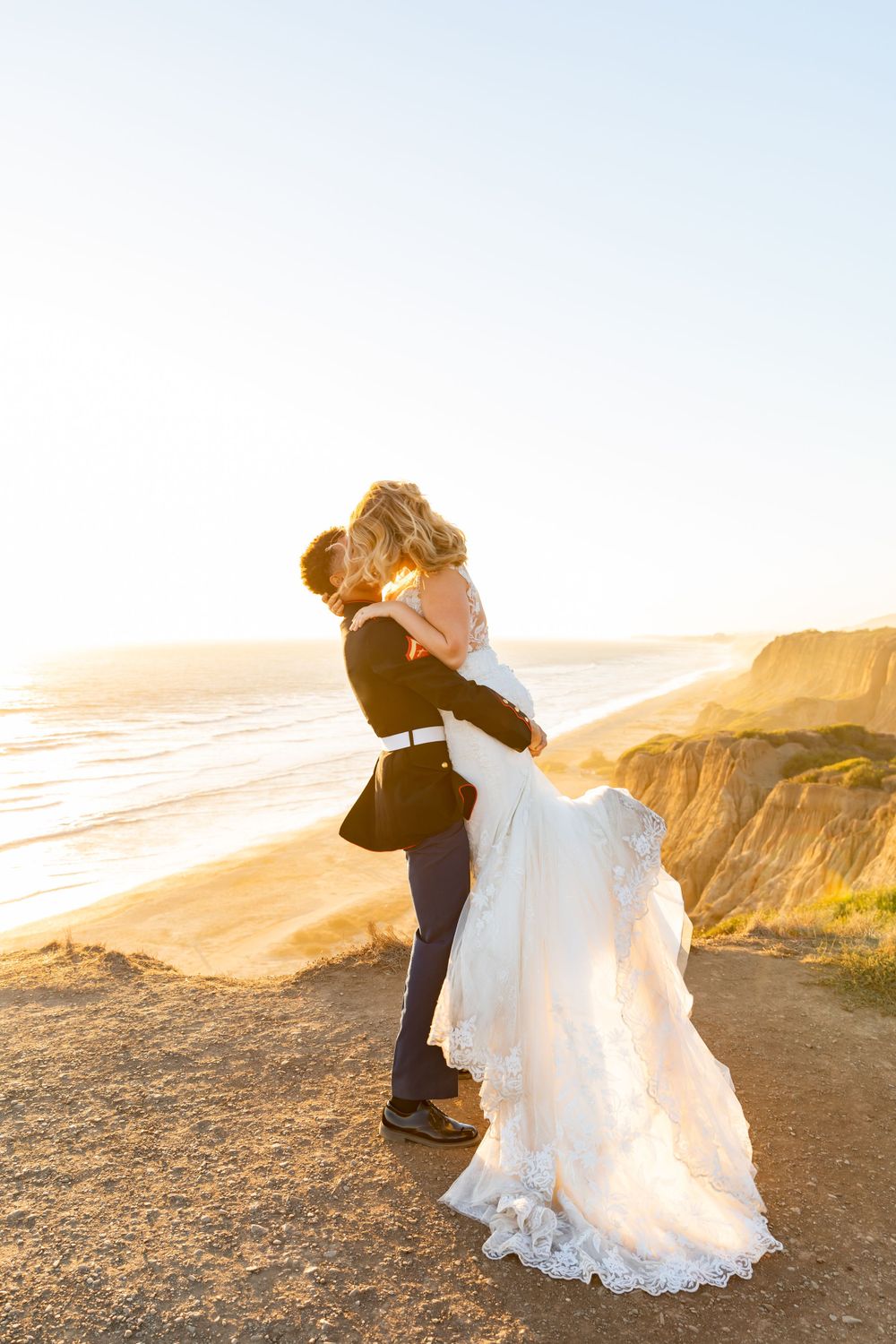 A romantic sunset embrace between newlyweds on a scenic coastal cliff.