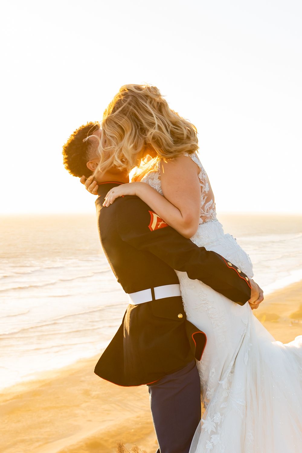 A joyful wedding moment captured in golden sunlight on a dramatic coastal overlook.