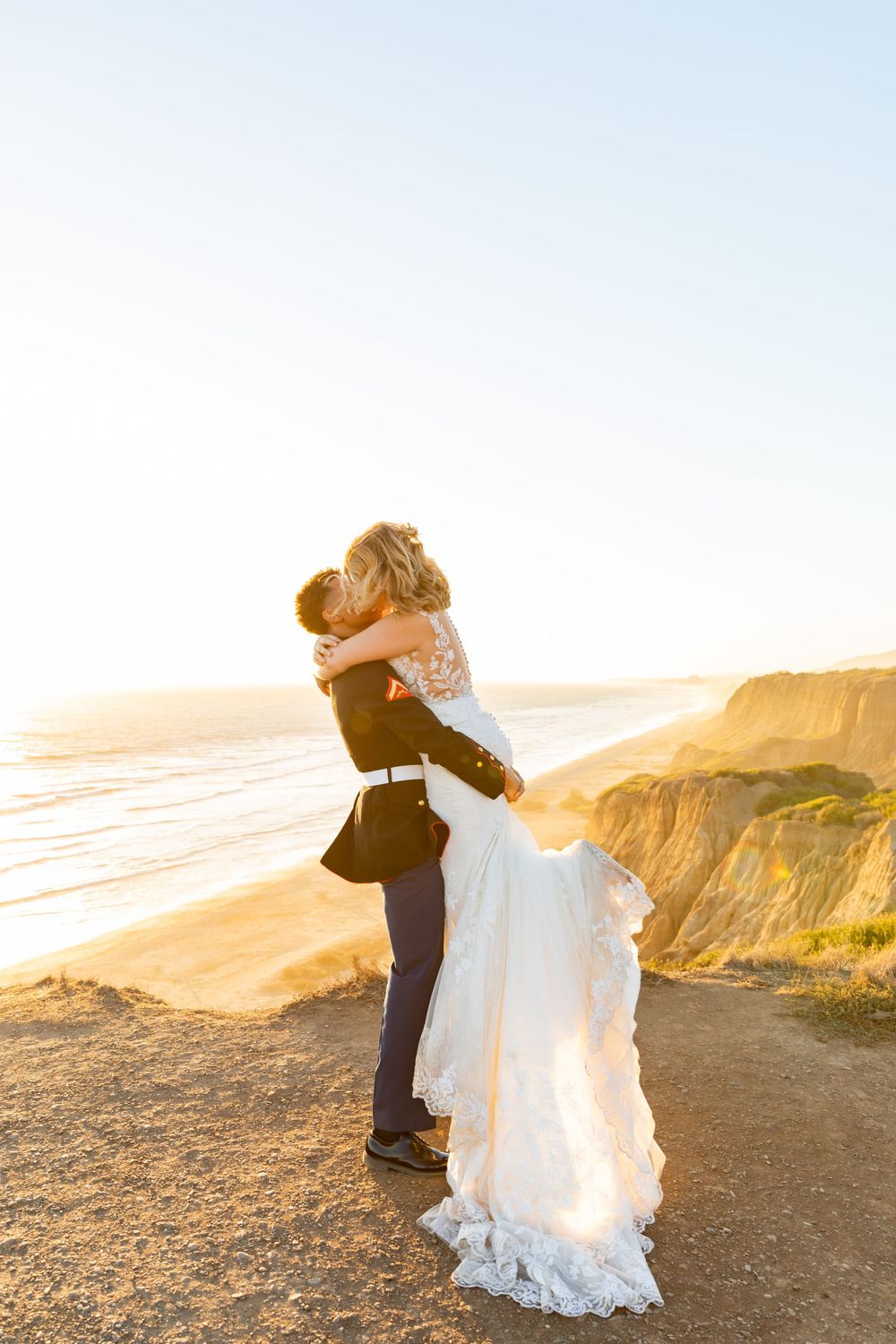A sunset wedding portrait showing a loving embrace against golden coastal cliffs.