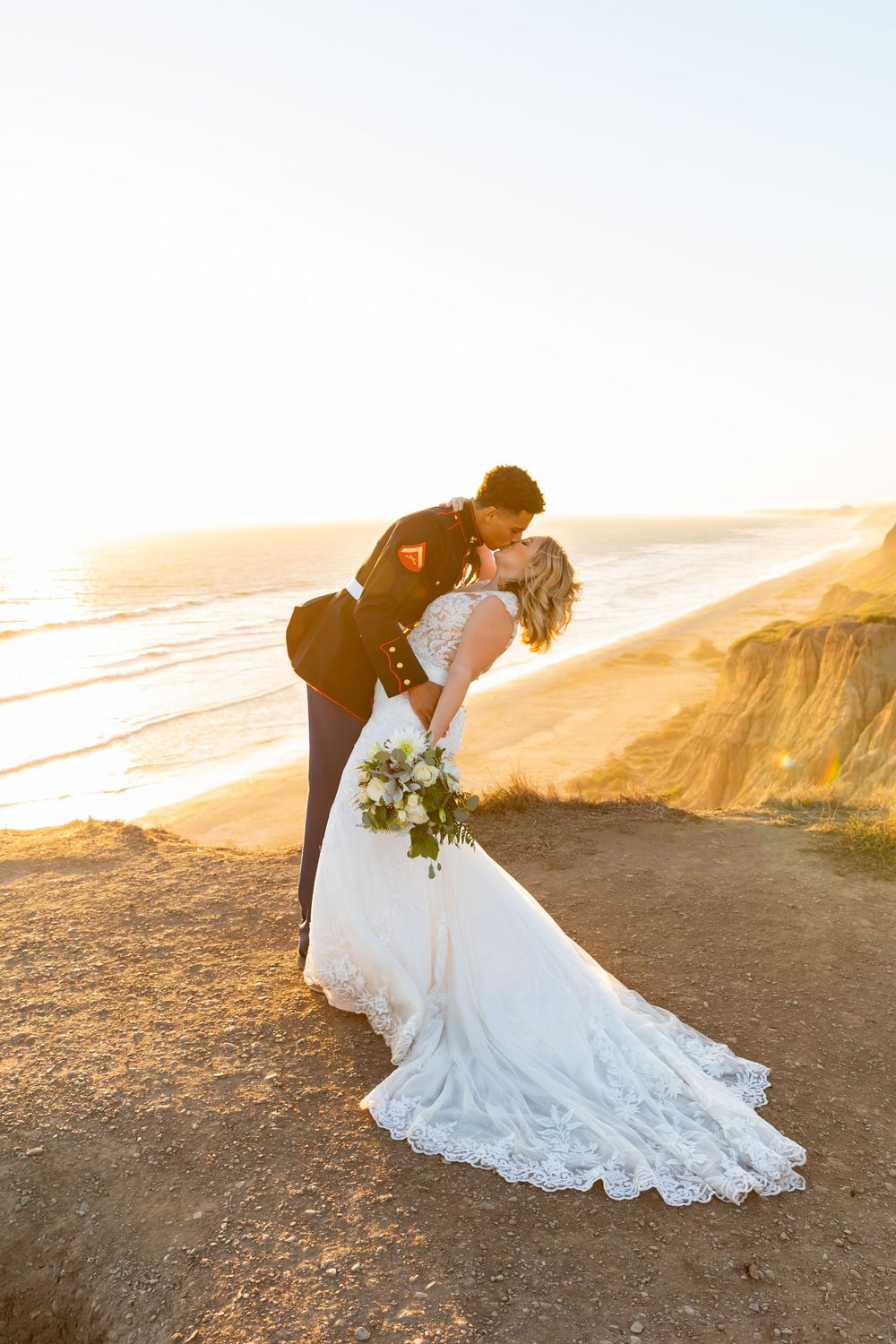 Wedding couple in classic dip pose with dramatic coastal backdrop at golden hour.