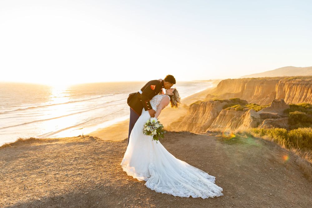 Golden hour wedding portrait with dramatic coastal cliff backdrop.
