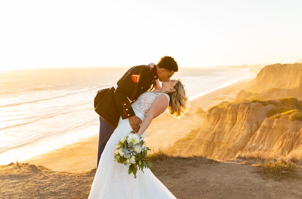 Sunset wedding photo with couple in romantic pose against coastal landscape.