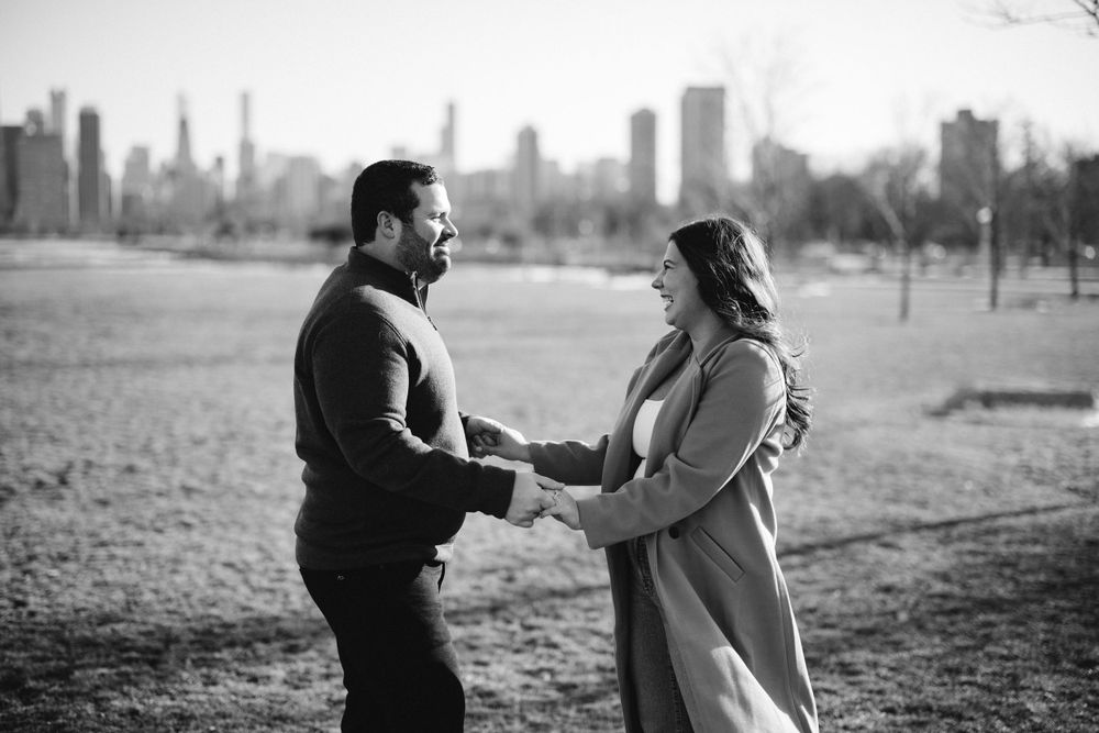 Couple poses against the shimmering waters of Lake Michigan during engagement shoot