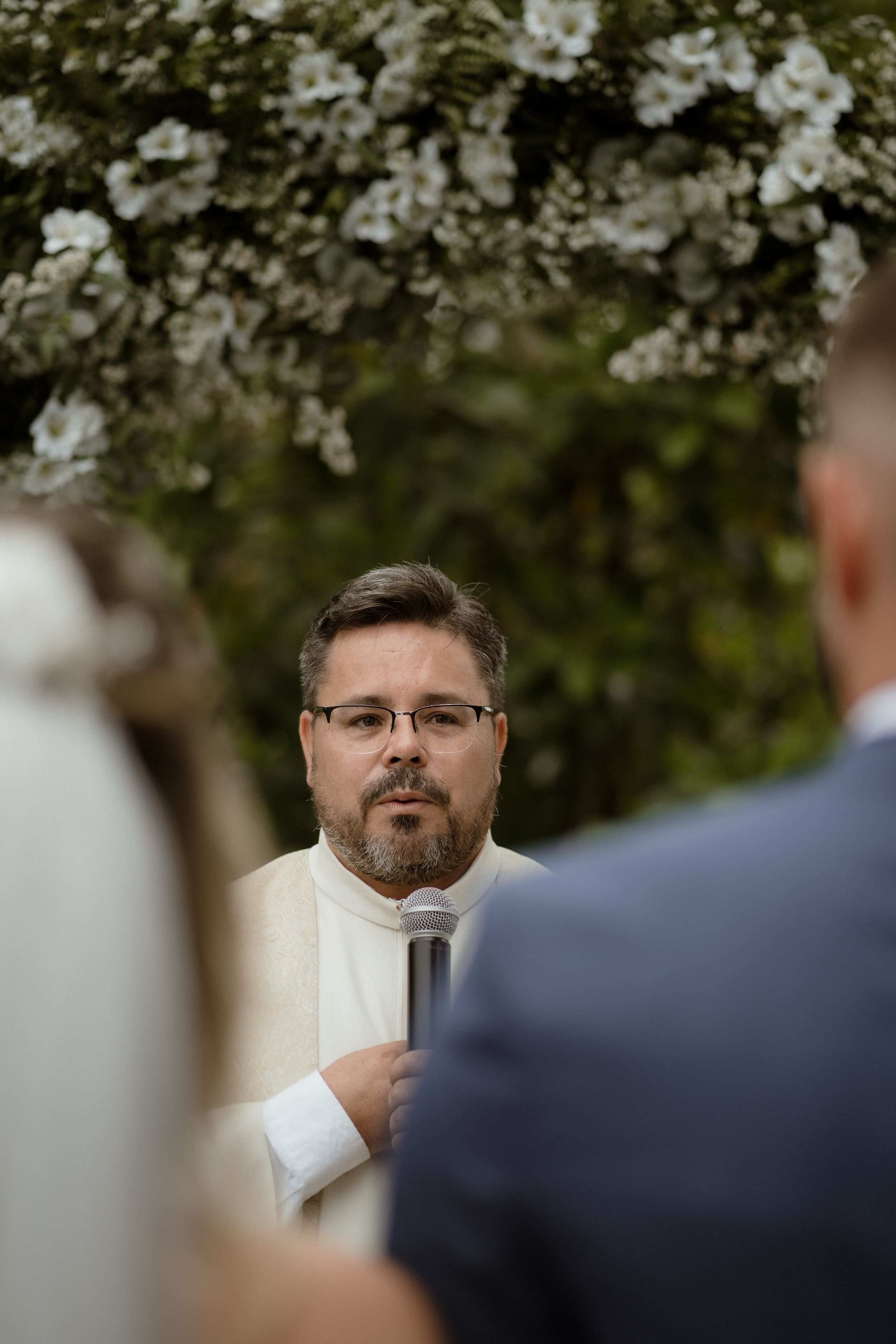 A close-up view of a person speaking during an outdoor wedding ceremony.