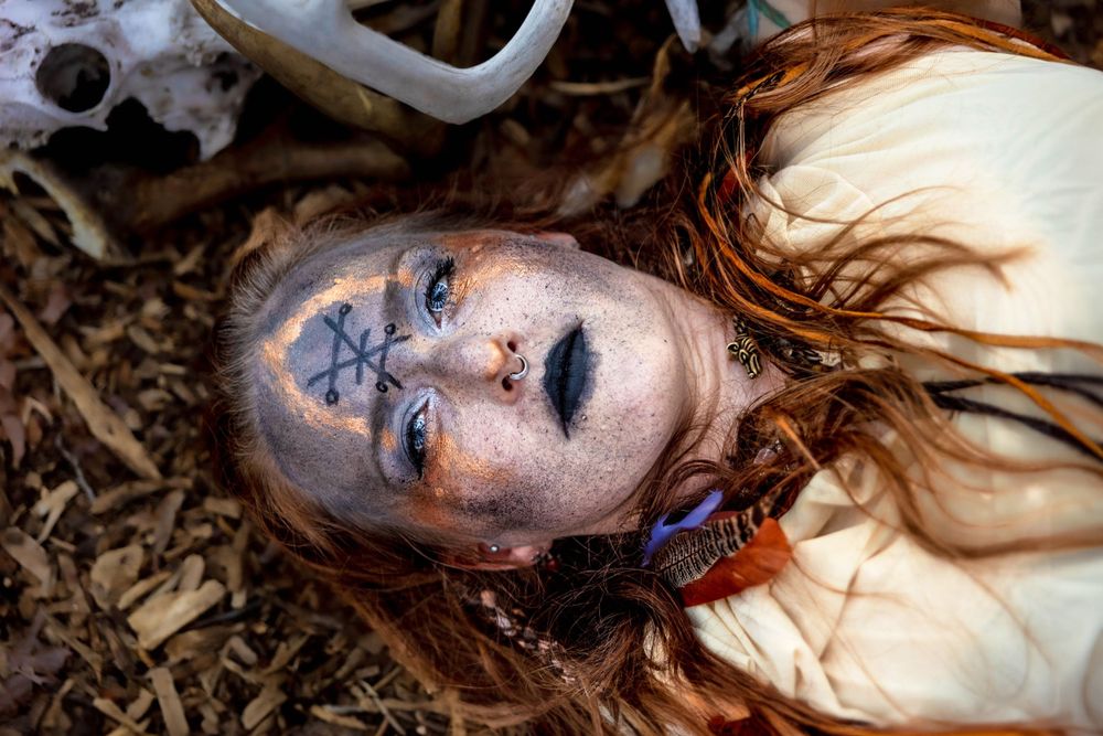 A bohemian witch lays in the leaves.