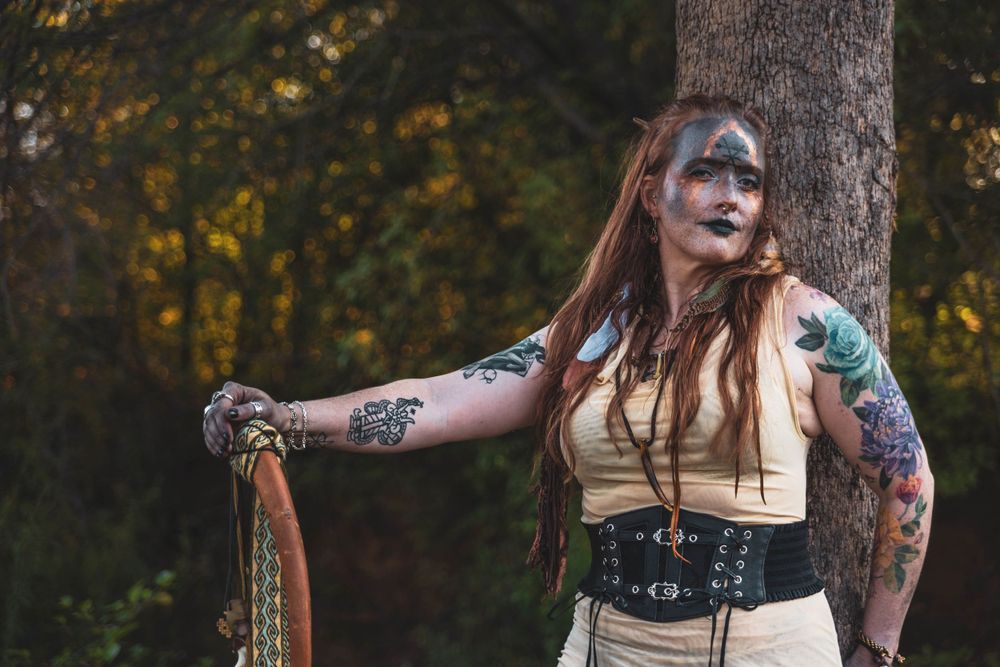 a bohemian witch poses with a tree.