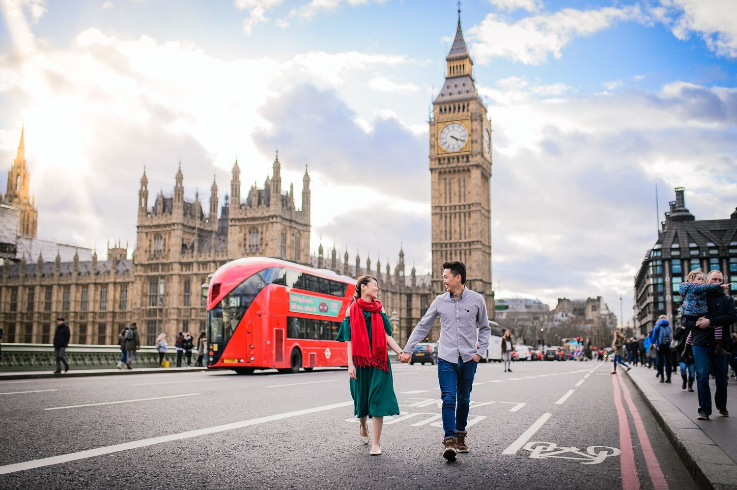 Pre-wedding couple walk across Westminster Bridge with Big Ben and red bus in the background