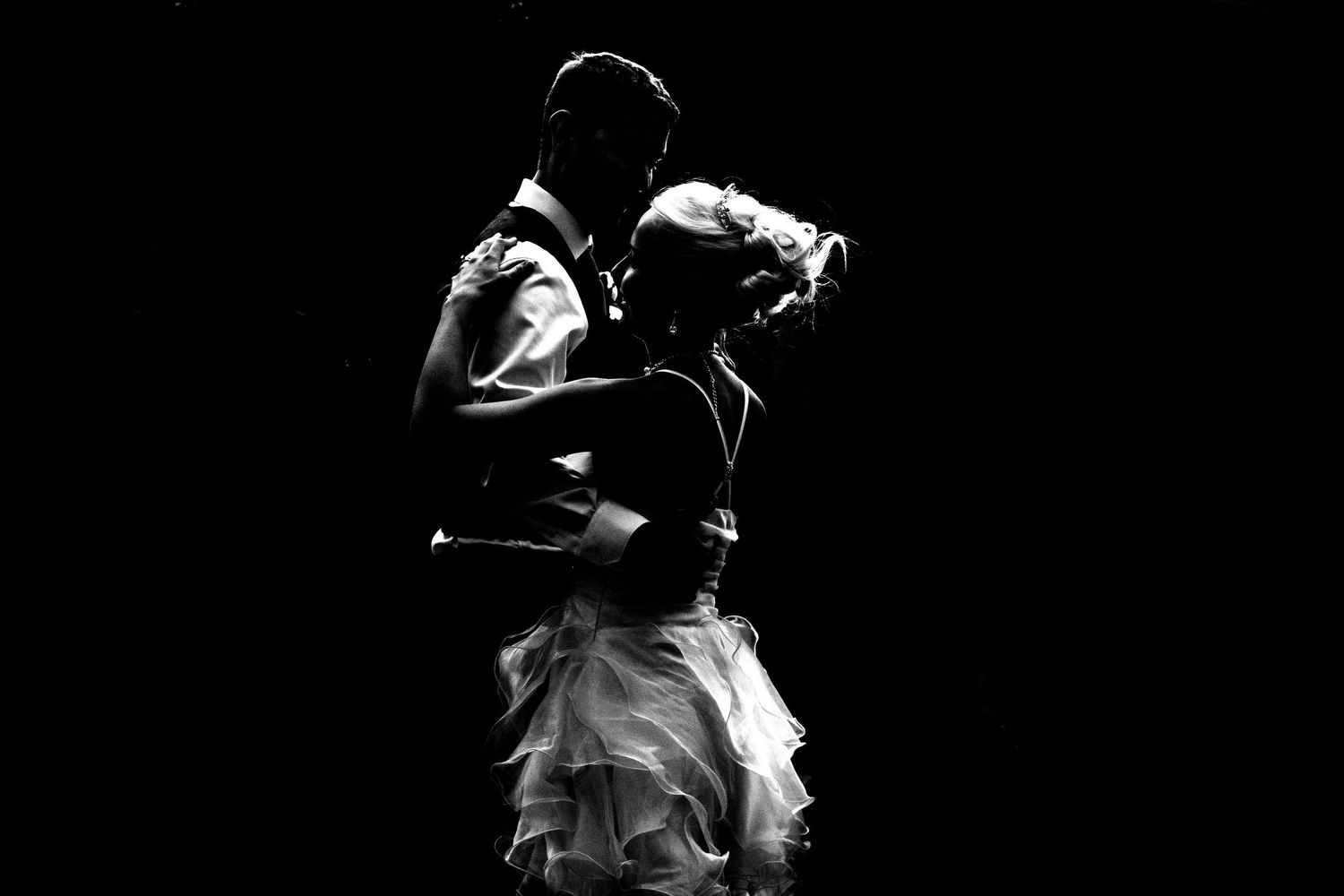 Dramatic silhouette of dancing couple against dark background.