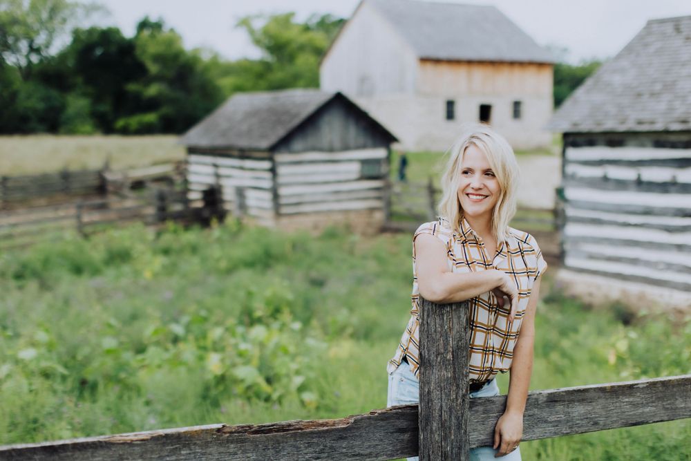 Rustic farm setting with wooden fences and historic buildings in background.