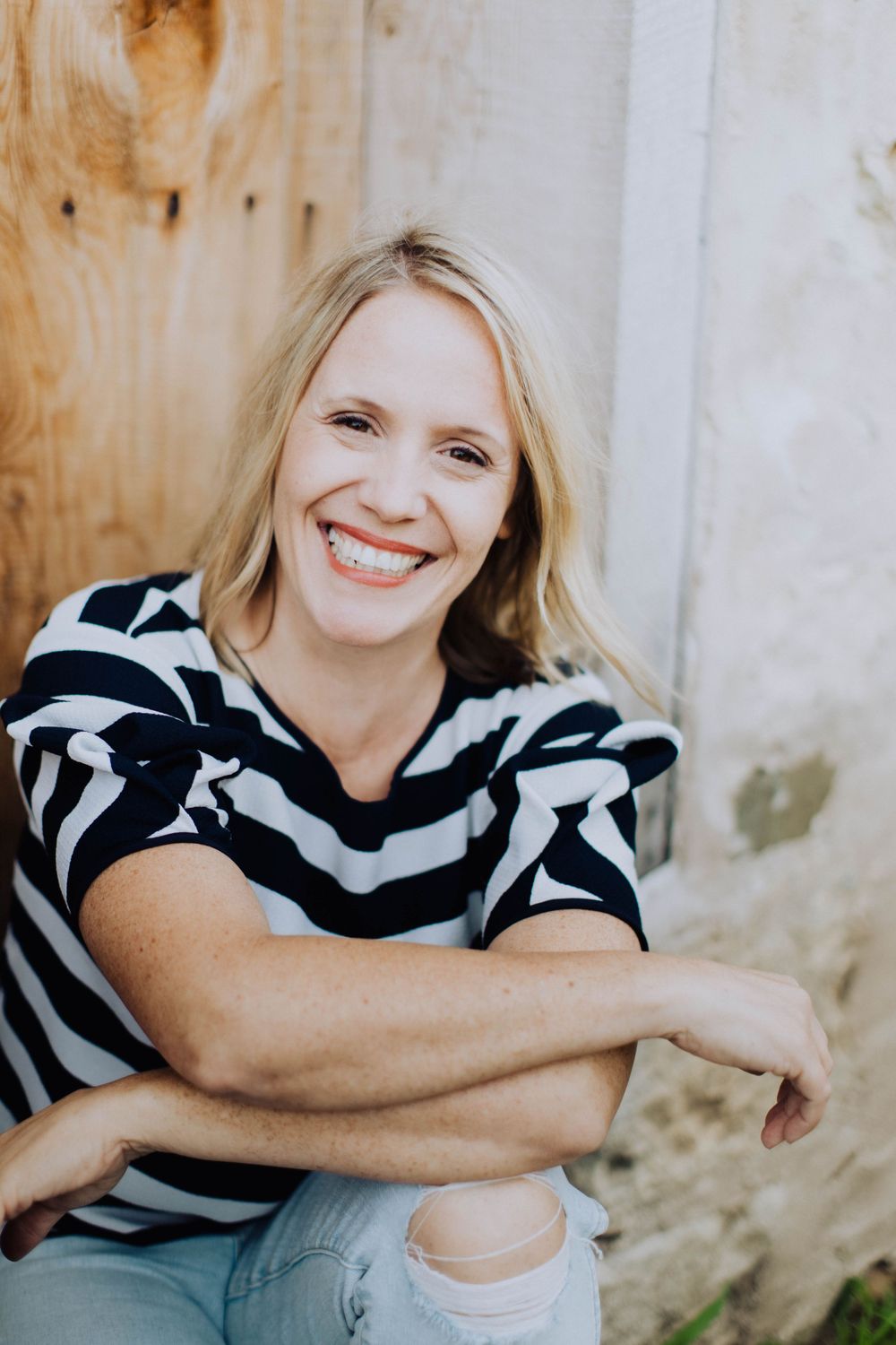 Portrait session against a light colored wall wearing a black and white striped top.