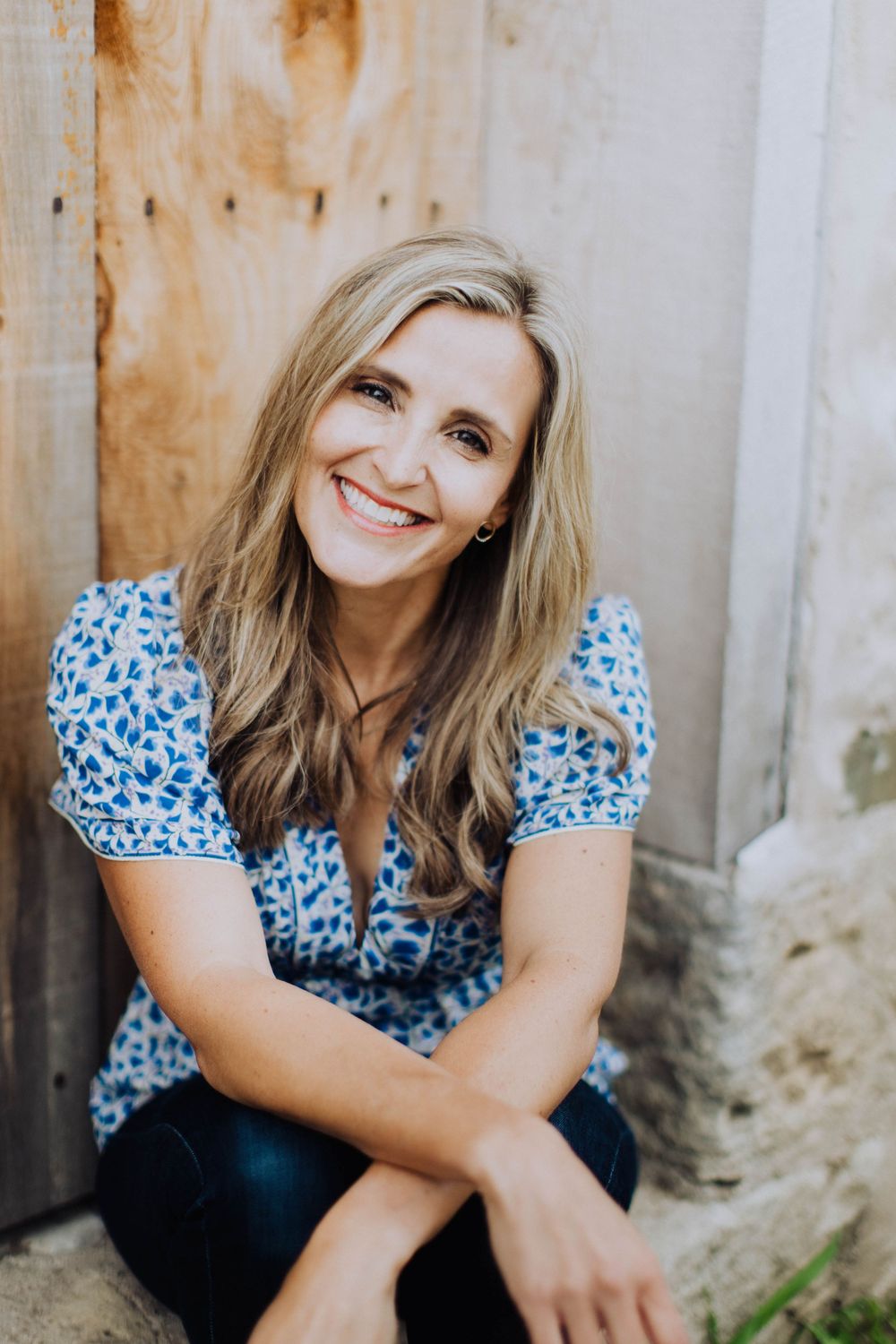 Casual portrait session against a rustic wall wearing a blue floral top.