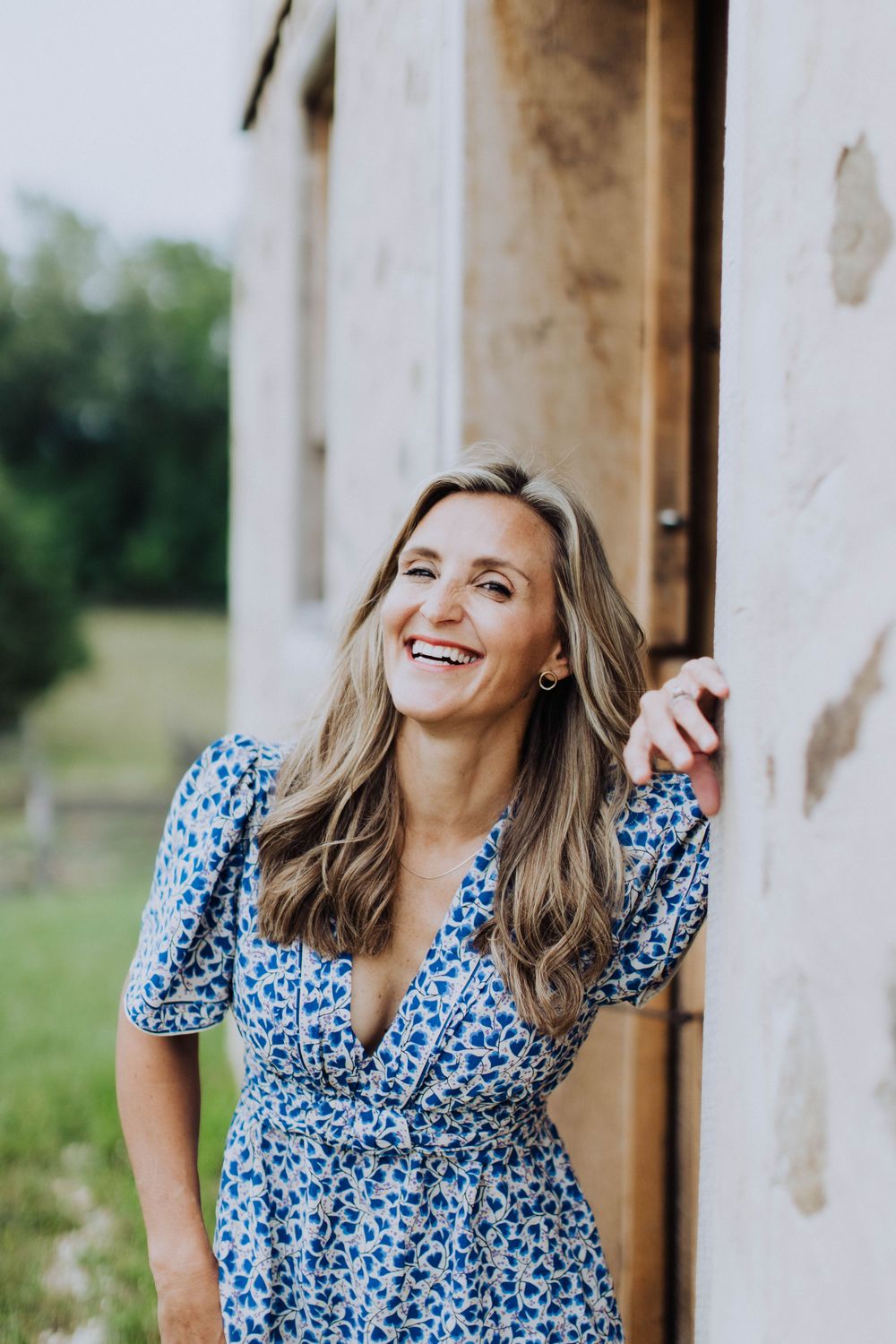 Candid portraits in a blue floral dress against rustic white wall background.