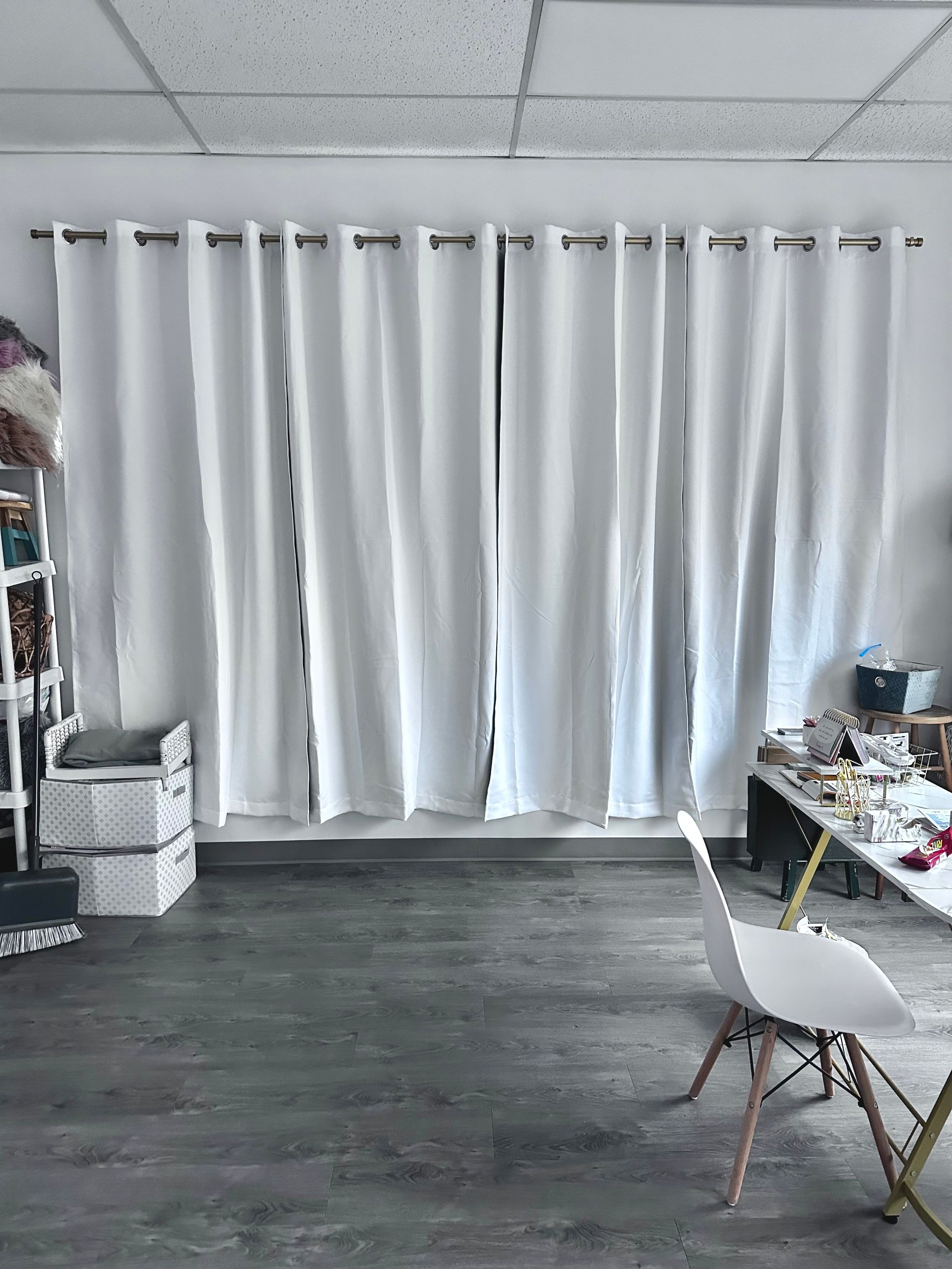 Modern photography studio with white curtains and gray flooring.