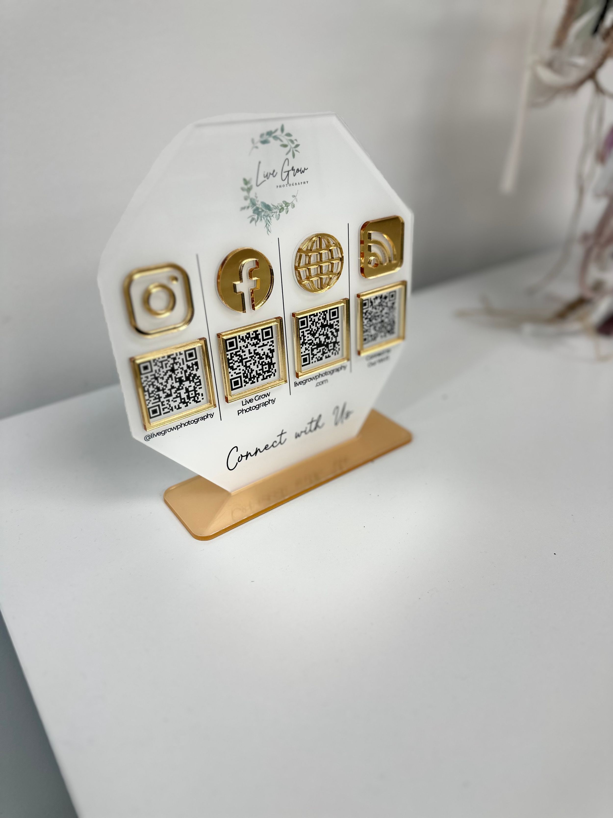 Social media QR code display stand with gold icons on white hexagonal base.