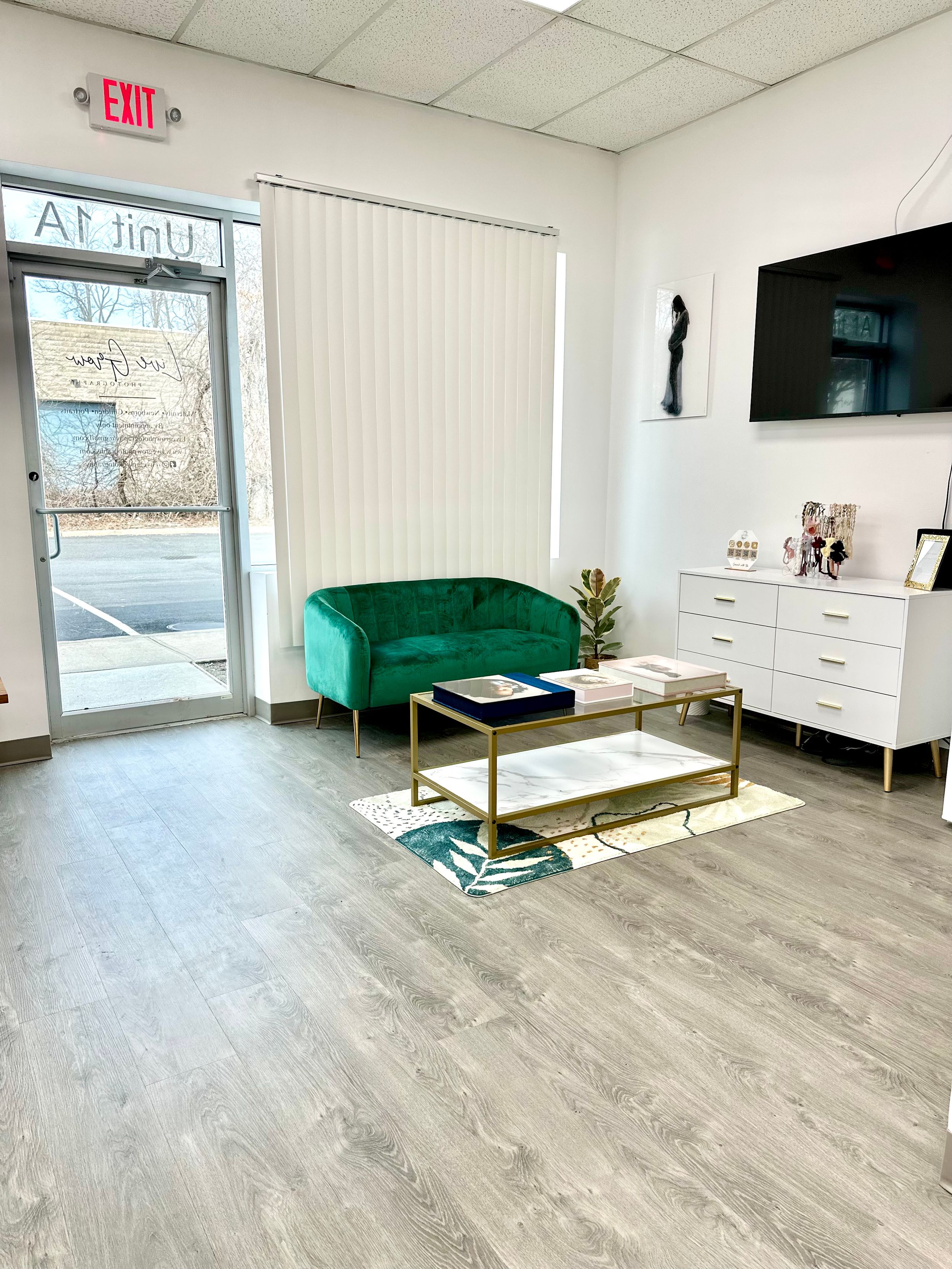 Reception area with emerald sofa, glass coffee table, and exit door.