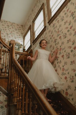 A joyful pose on a vintage staircase with floral wallpaper and natural light streaming in.