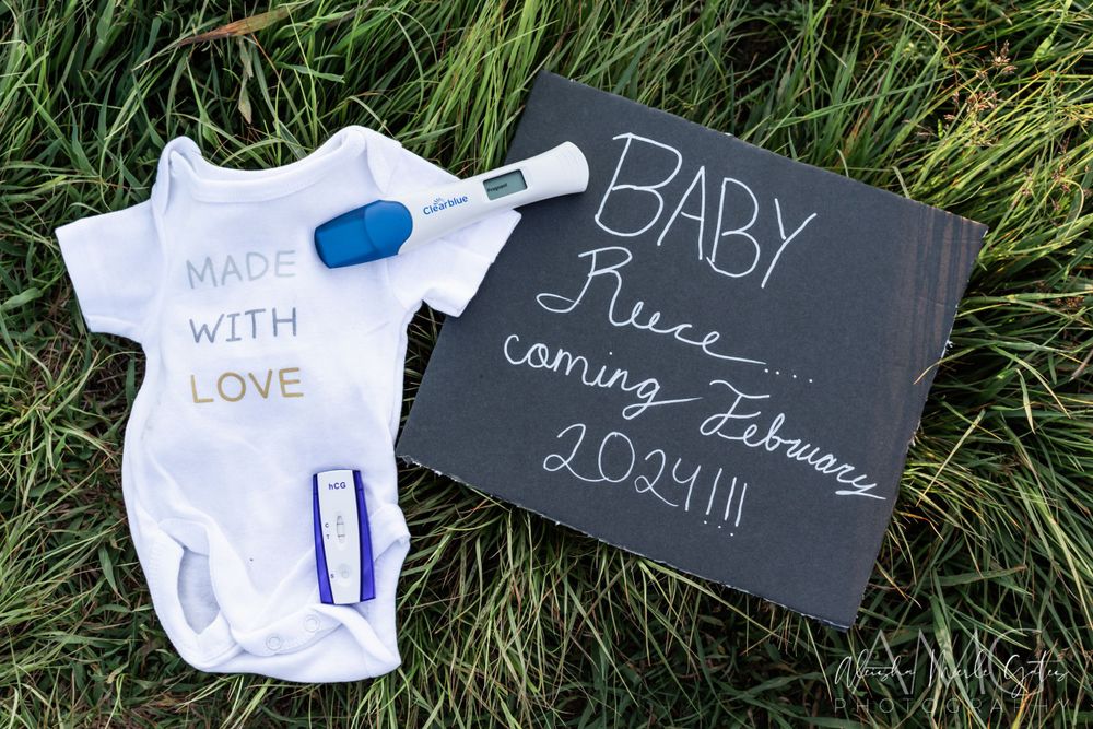 Pregnancy announcement with onesie, positive test, and chalkboard sign, coming February 2024. Maternity Announcement Photographer.