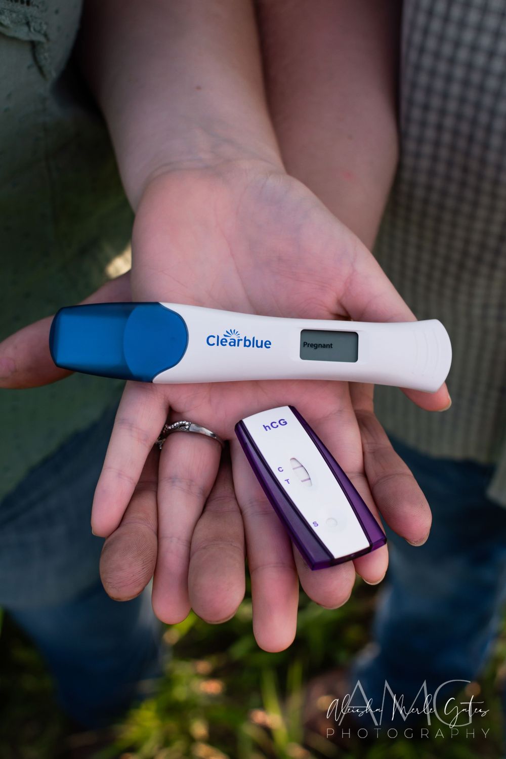 Couple holding a Clearblue digital pregnancy test & hCG test strip, showing positive results, outdoors. Maternity Announcement Photographer.