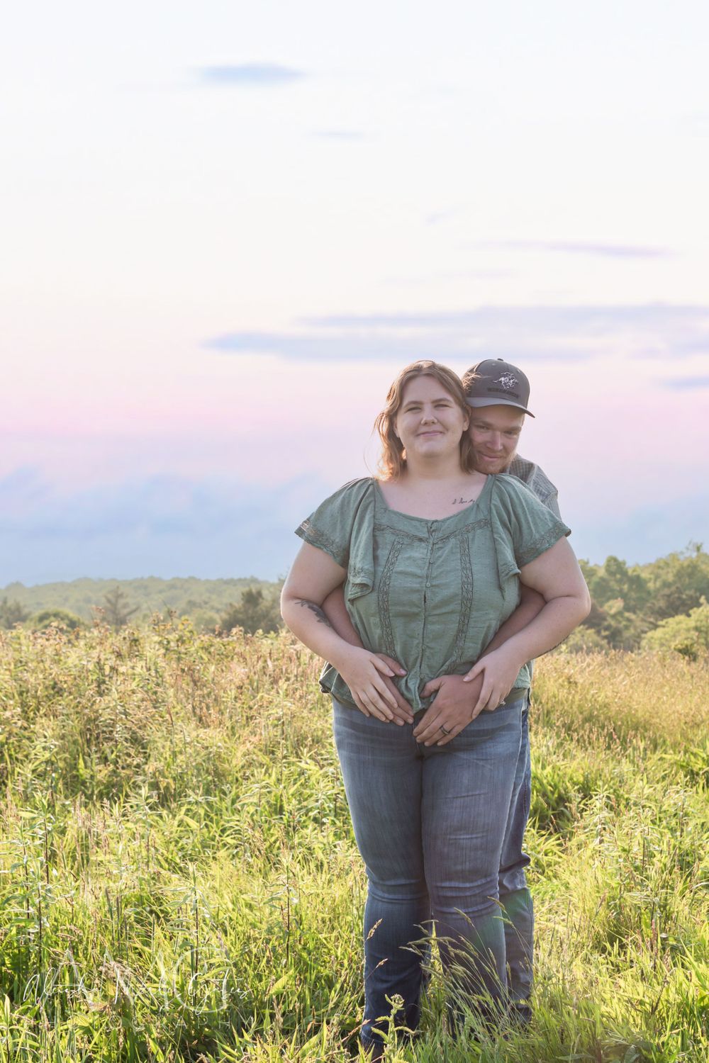 Full view of couples holding hands from behind making a heart shape on mothers stomach. Maternity Announcement Photographer.