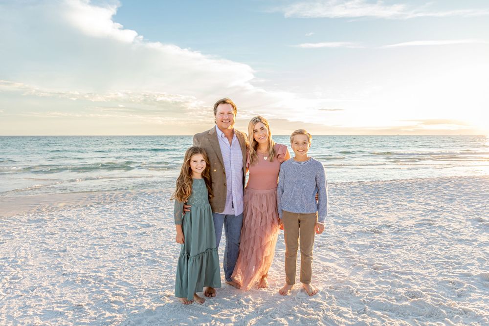 Family portrait session on a pristine white sand beach with gentle waves and sunset sky.
