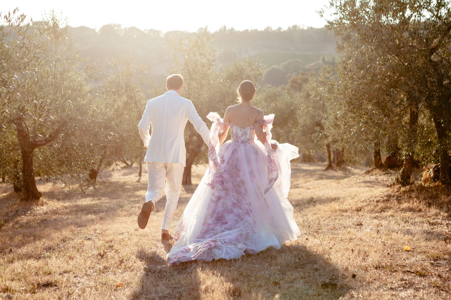 bride and groom run through an olive groom at sunset