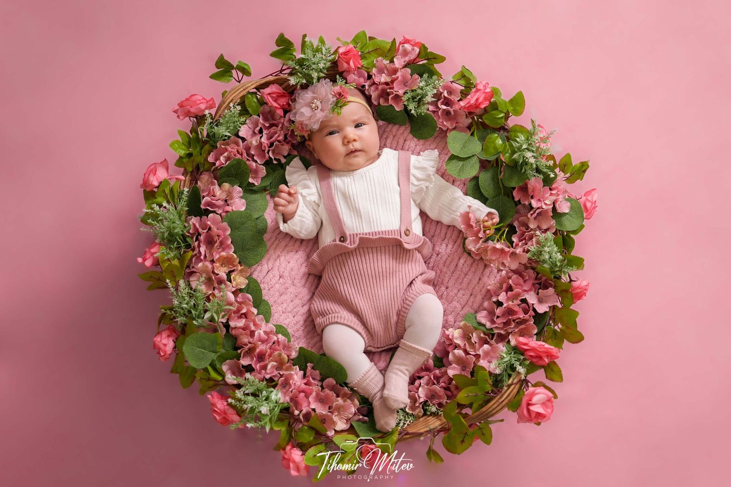 Бебешка фотосесия на момиченце на розов фон в кръгъл кош с розови и бели цветя