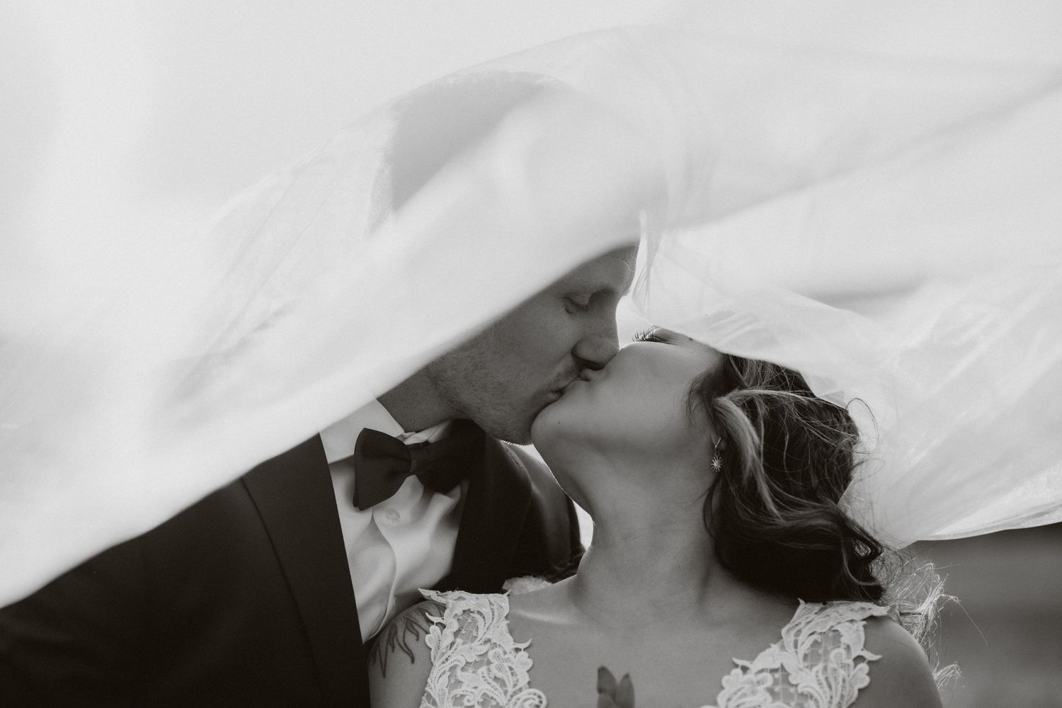 Bride and groom standing under bridal veil for wedding portrait. Photos taken at Red Star Ranch in Kelowna