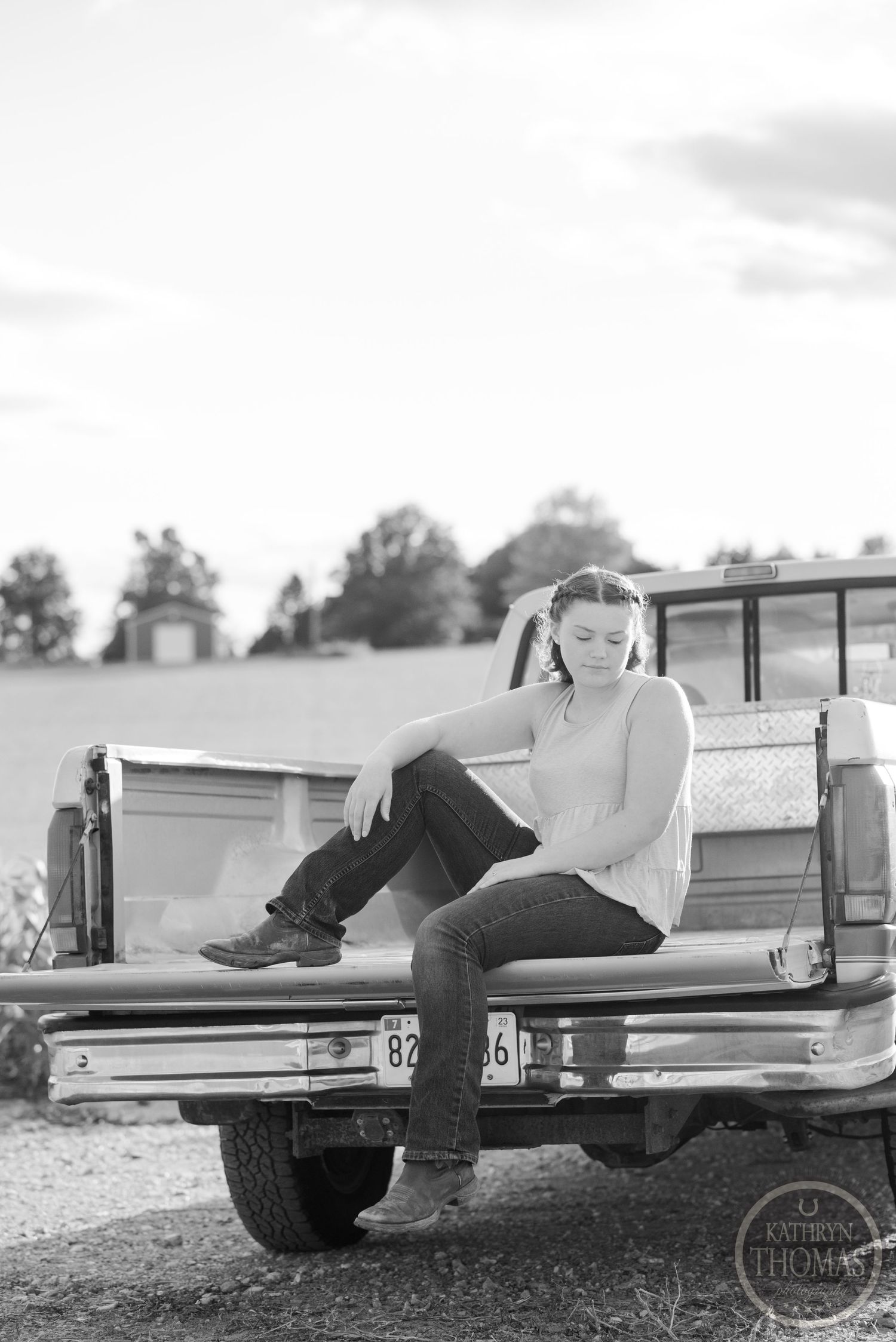 Black and white photo of someone relaxing in the bed of a classic pickup truck.