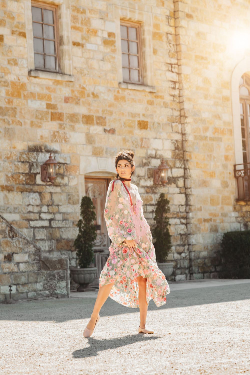 A playful fashion series against a rustic stone building in warm sunlight.