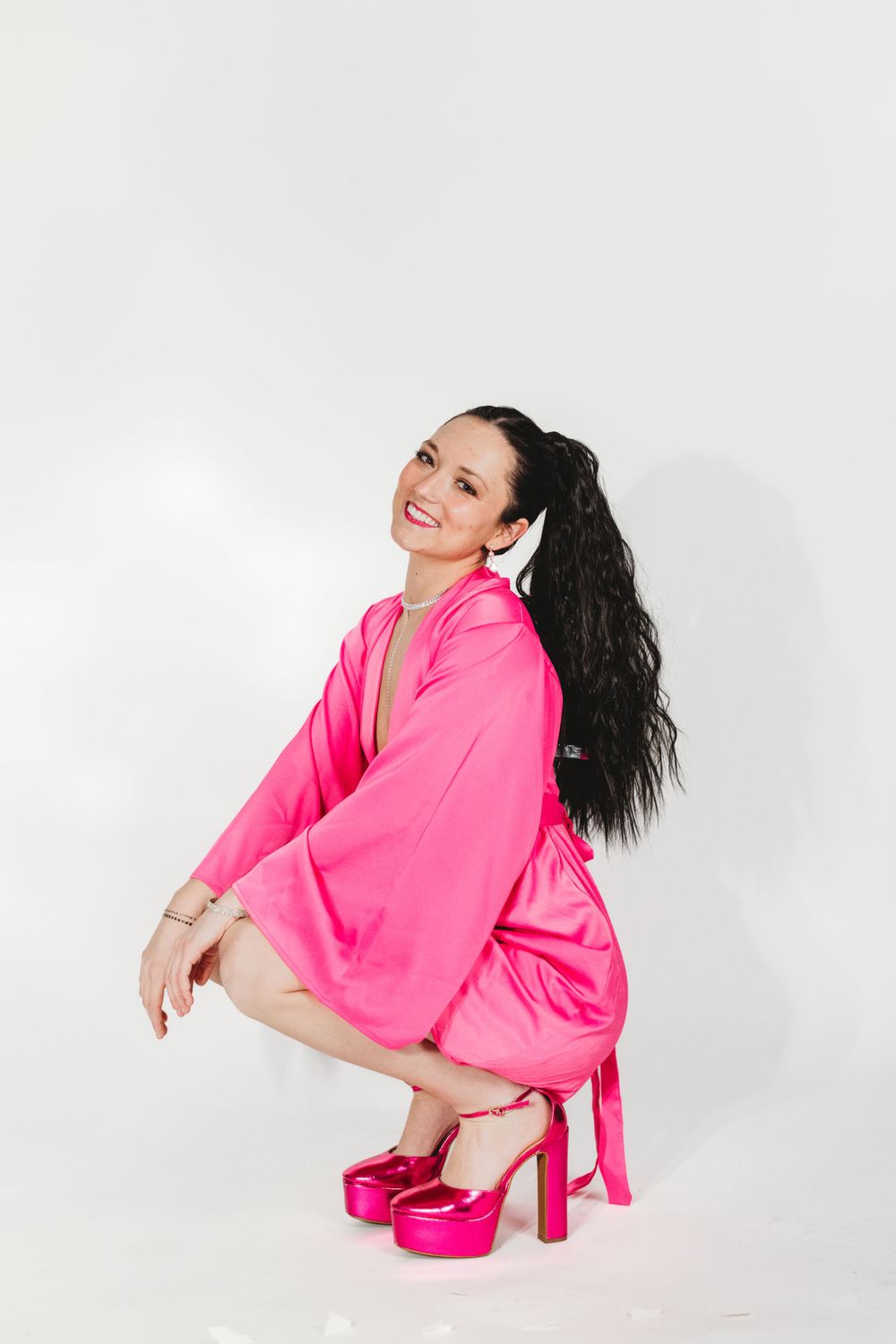 A dynamic fashion photo series featuring a bright pink outfit against a white studio background.
