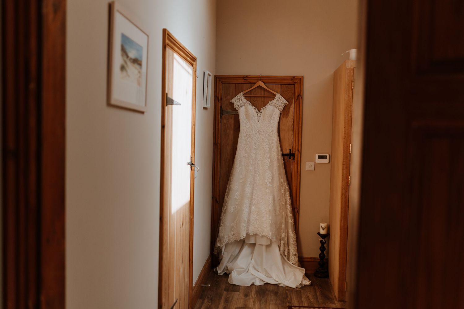 Dress hanging on door in farmhouse before wedding at Hollyhollows wedding venue and glamping