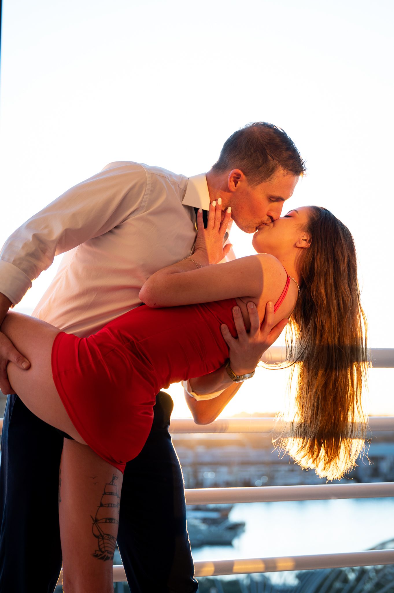 Couple kissing on a balcony with the sun behind