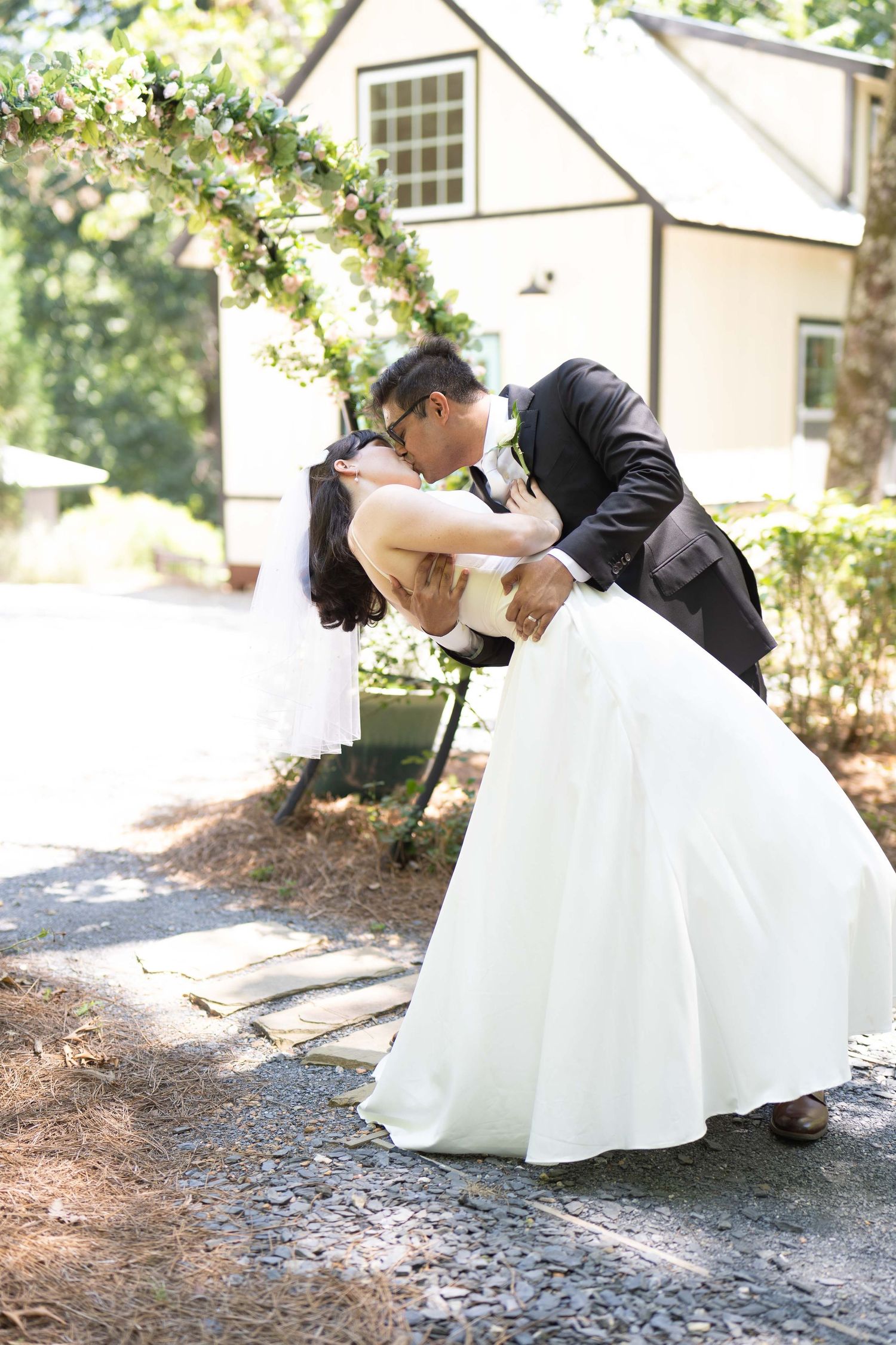 A romantic dip pose on a sunlit path shows a couple in wedding attire sharing an intimate moment. Mableton GA Kelly Photography Atlanta