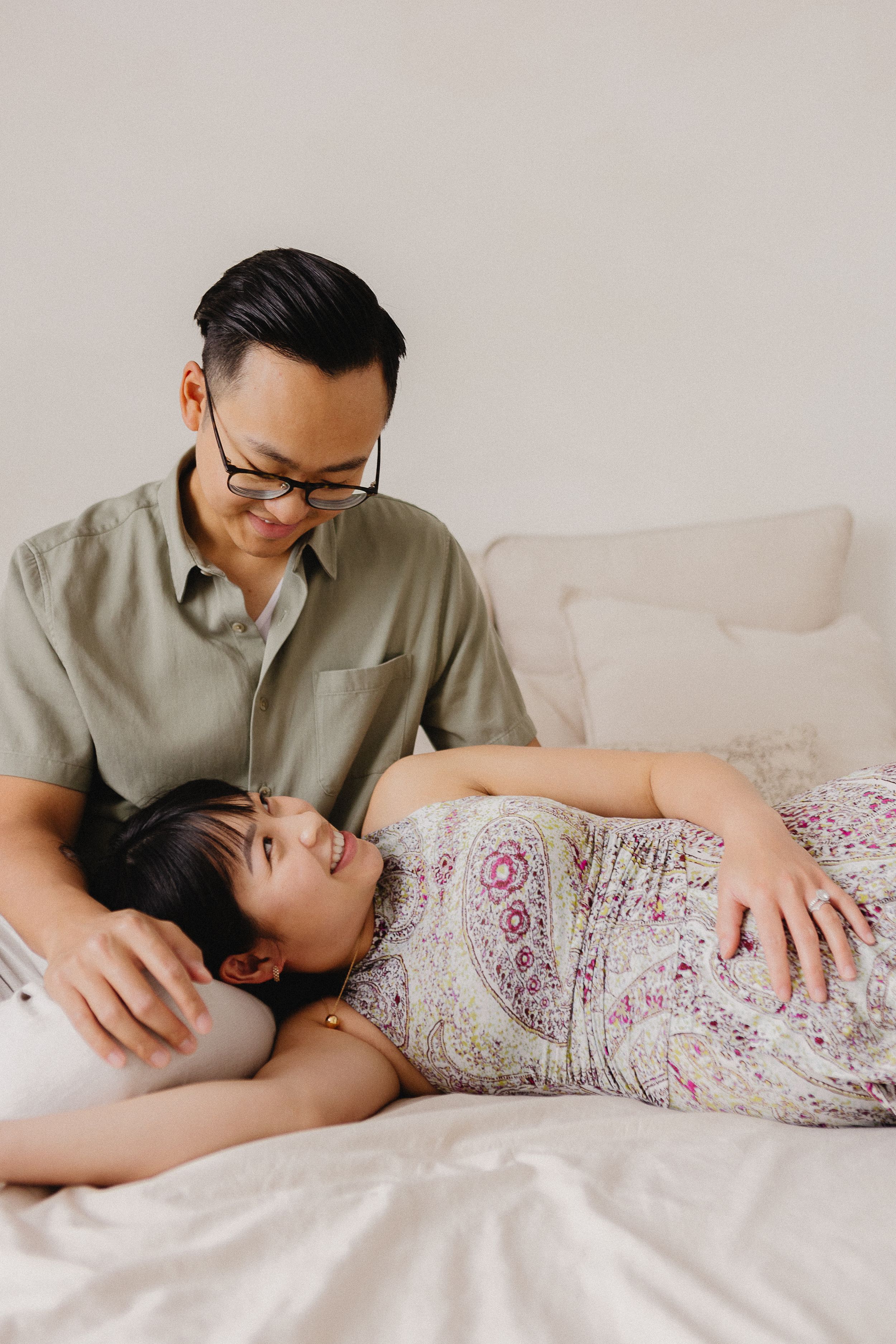 Intimate couple relaxing together on white bedding in casual attire.