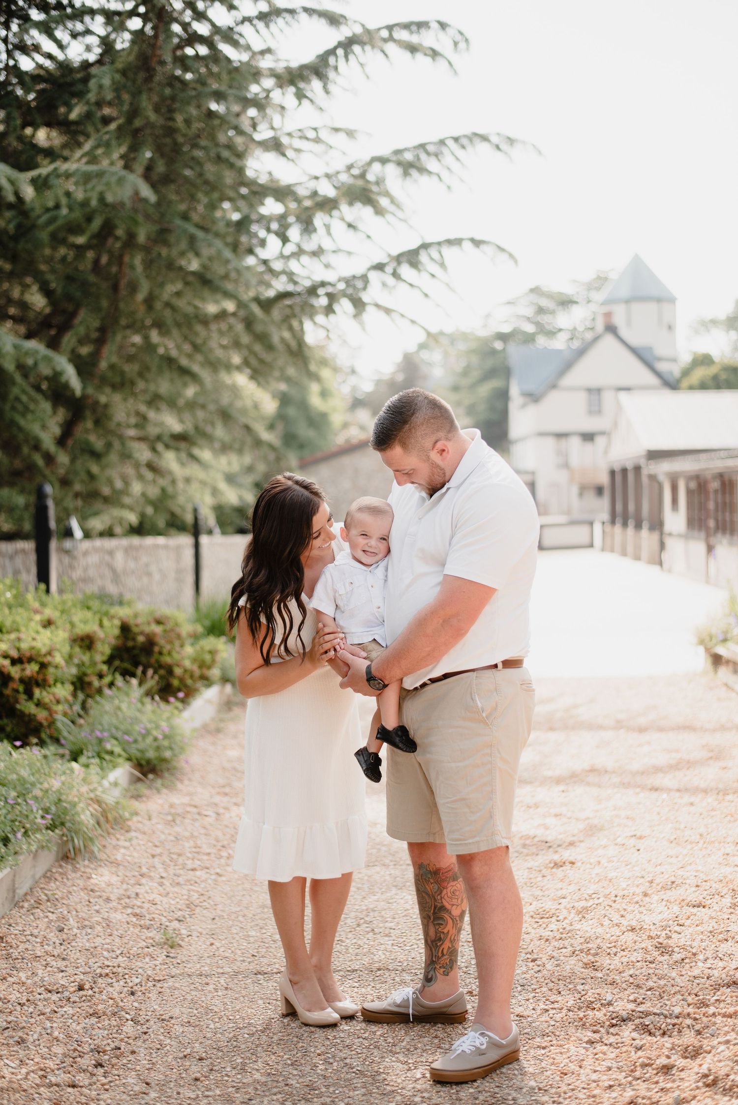 A tender family portrait captured on a scenic garden path with historic buildings in the background.