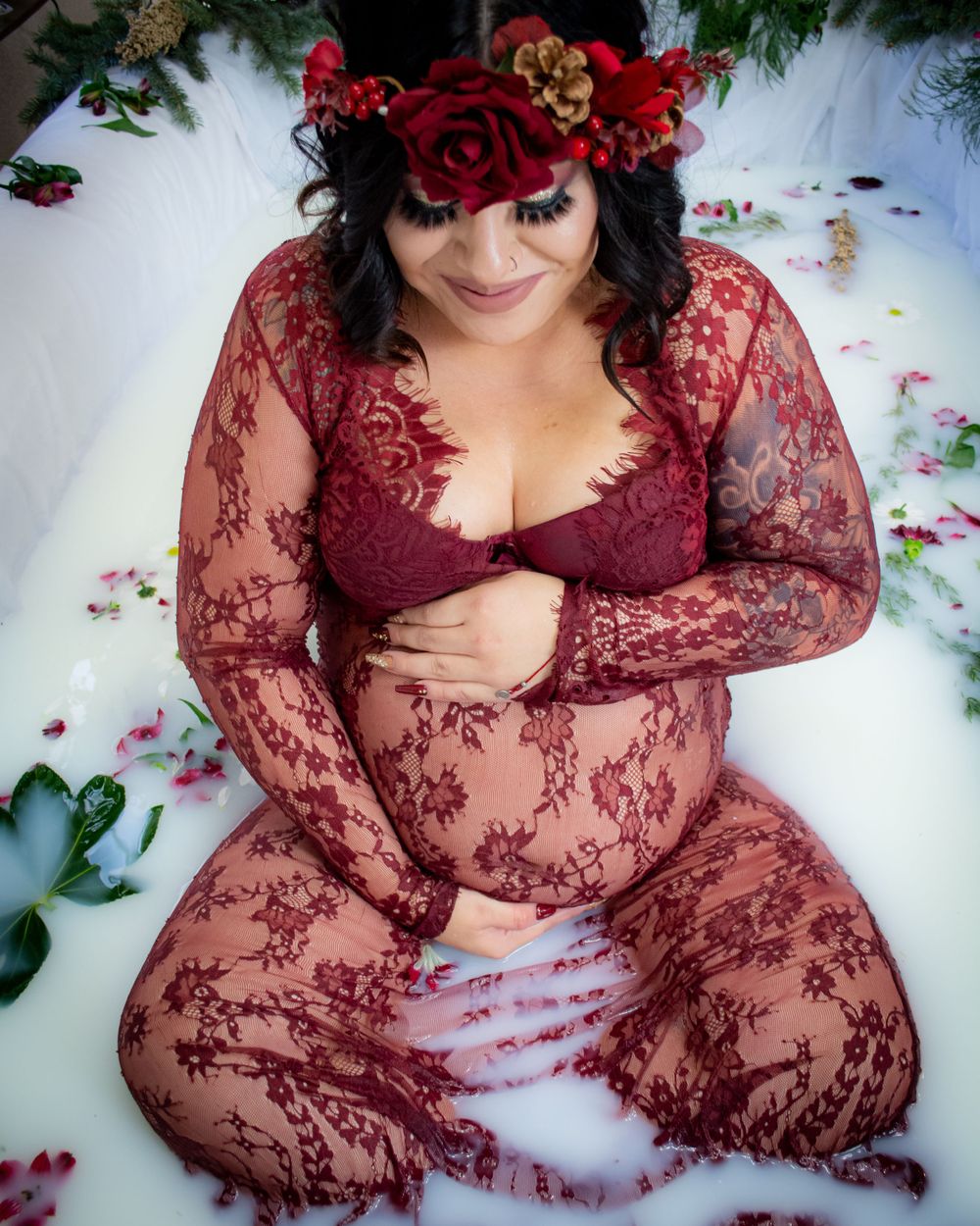 Artistic boudoir photography featuring burgundy lace and scattered rose petals.