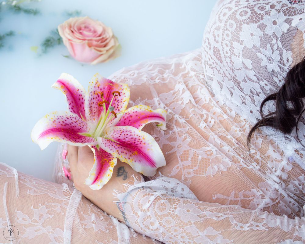 Romantic milk bath portrait with stargazer lilies and rose petals.