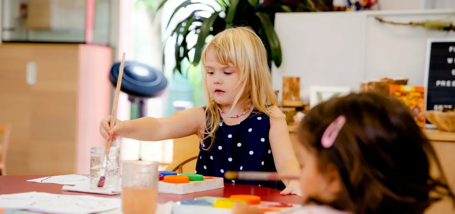 A creative workshop setup with art supplies and materials spread across a wooden table for crafting projects.