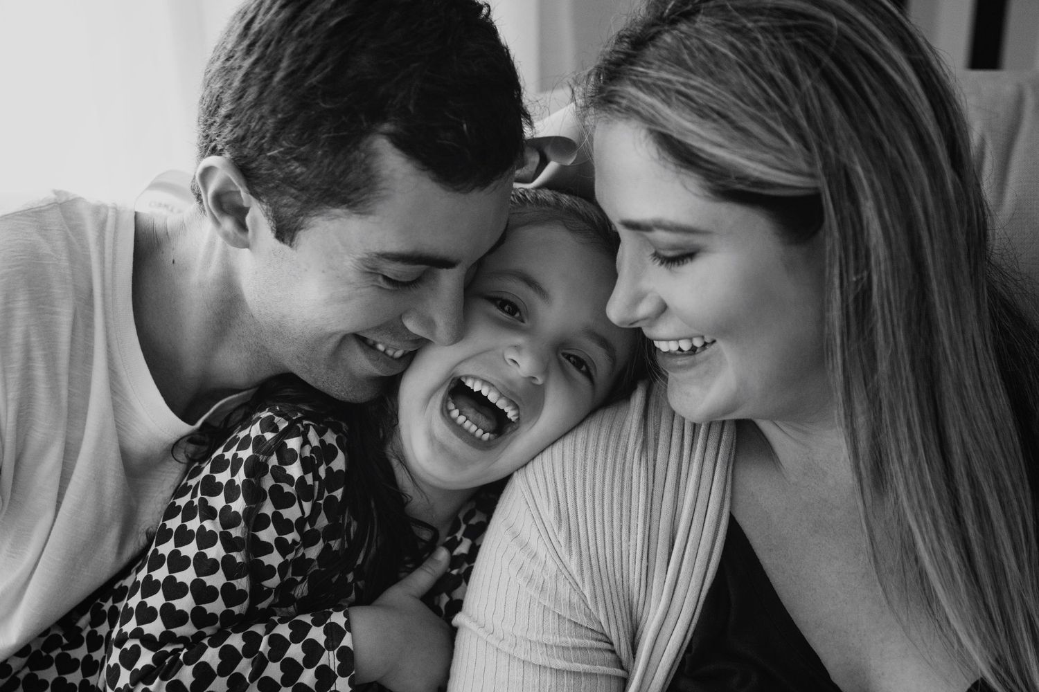 Black and white intimate family portrait showing genuine laughter and connection.