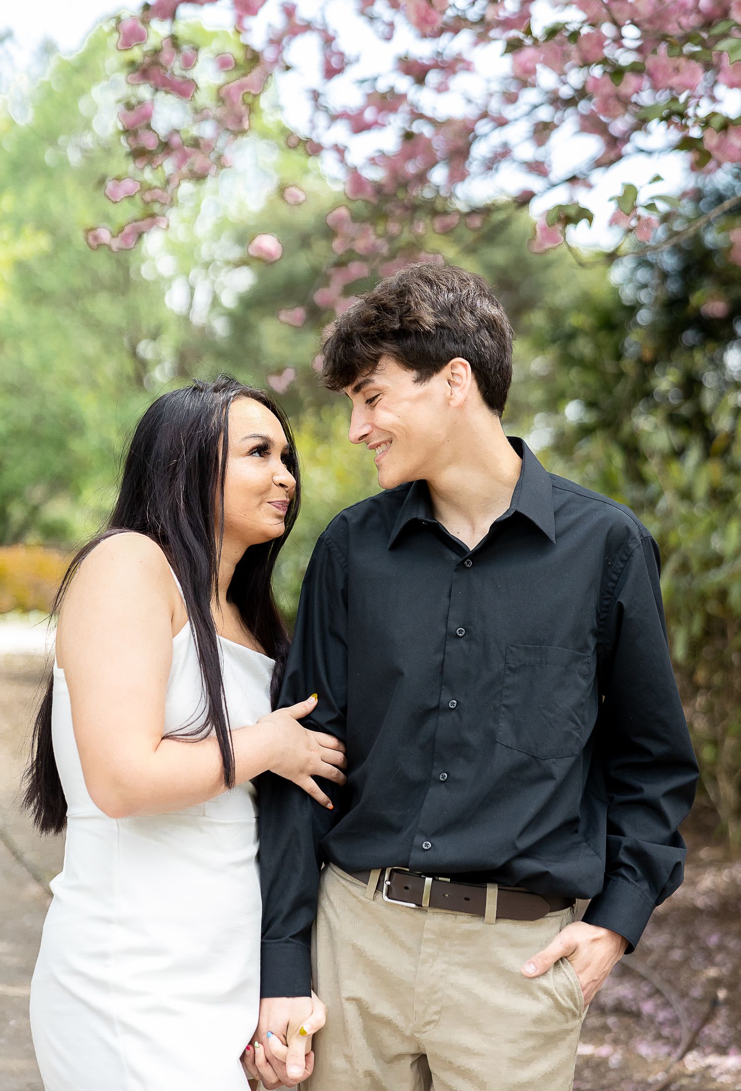 Couple sharing romantic moment under blooming cherry trees in spring garden.