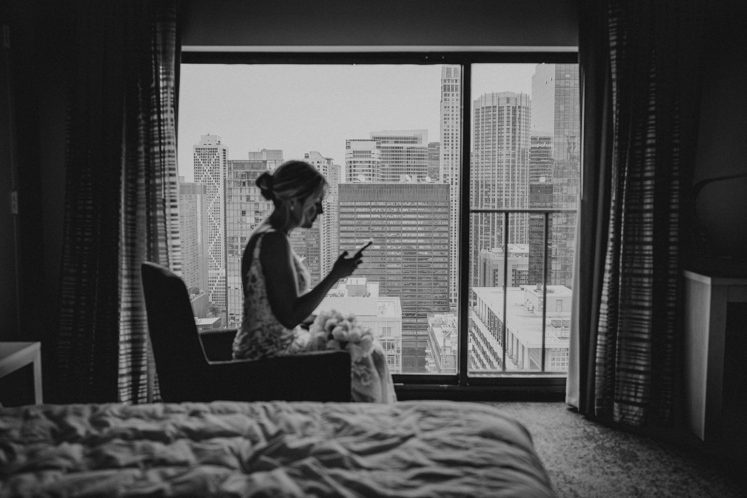 Silhouette by window in city apartment with skyline view.