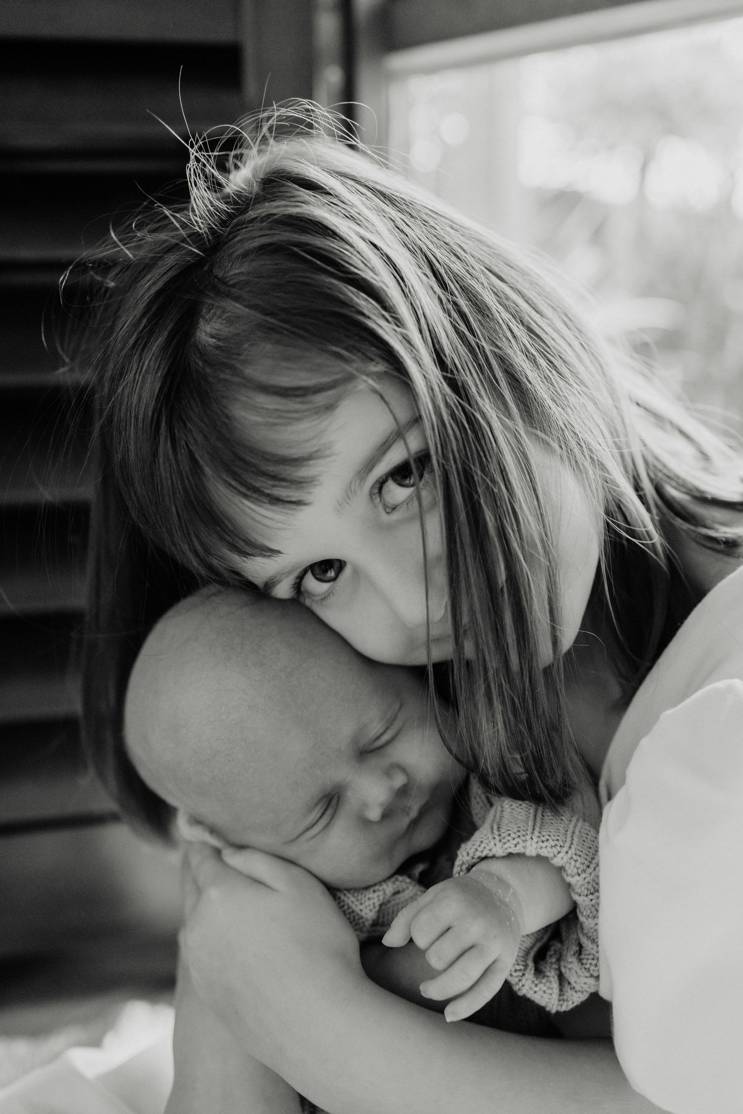 Intimate black and white portrait showing tender moment with sleeping baby.