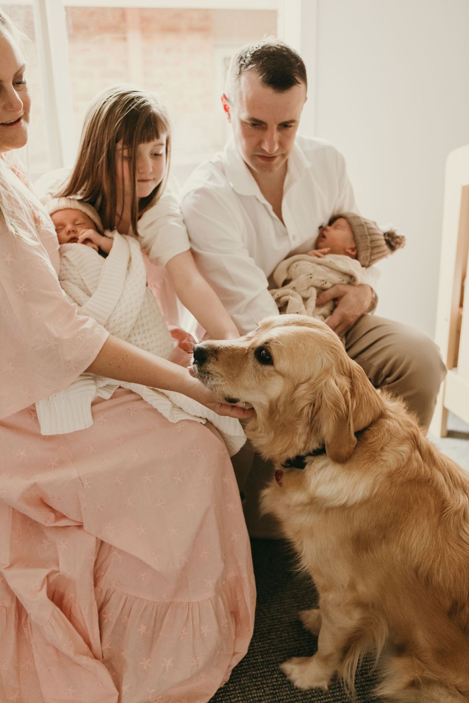 A family gathering in a nursery with their golden retriever beside them.