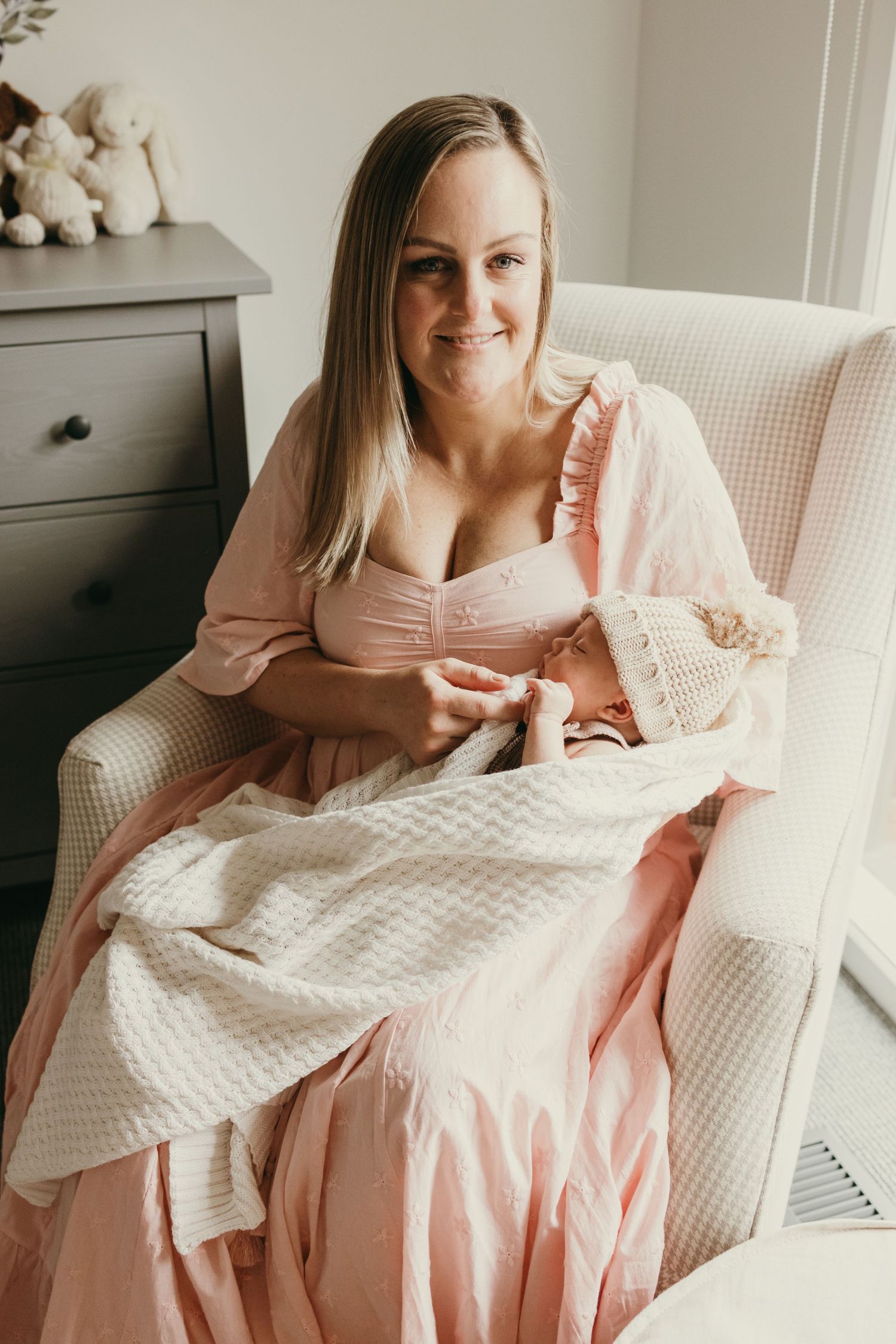 A tender moment in a nursery featuring soft pink decor and a white woven blanket.
