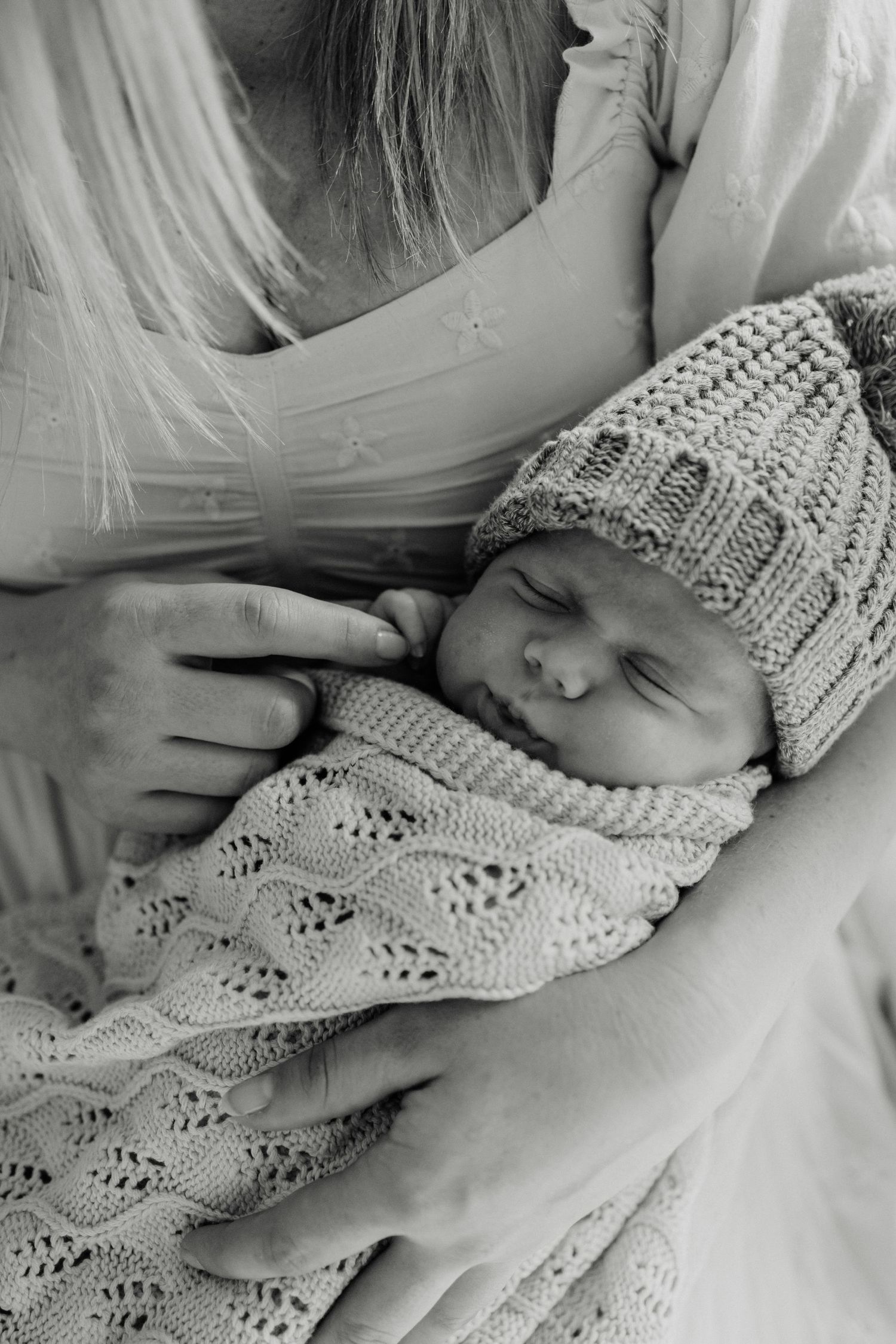 Black and white portrait of newborn in cozy knit sweater and hat sleeping peacefully.
