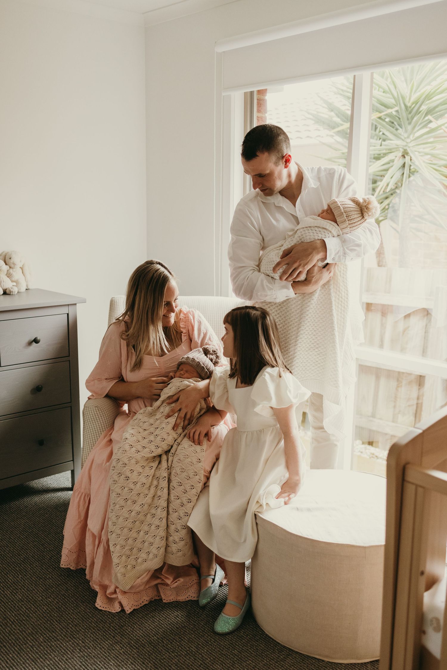 Intimate family moment in sunlit nursery room with natural decor.