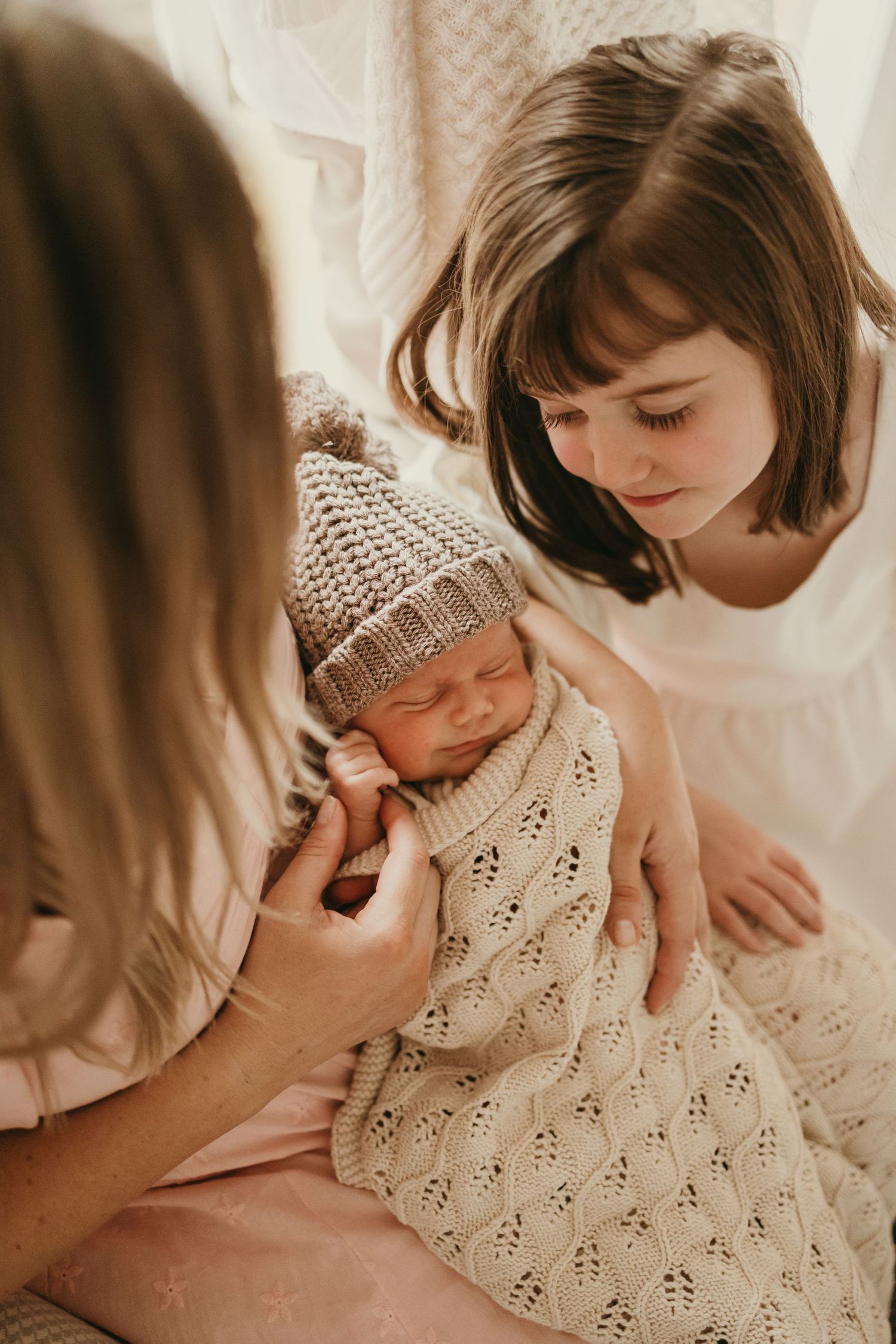 Intimate moment with sleeping newborn in knitted winter attire.