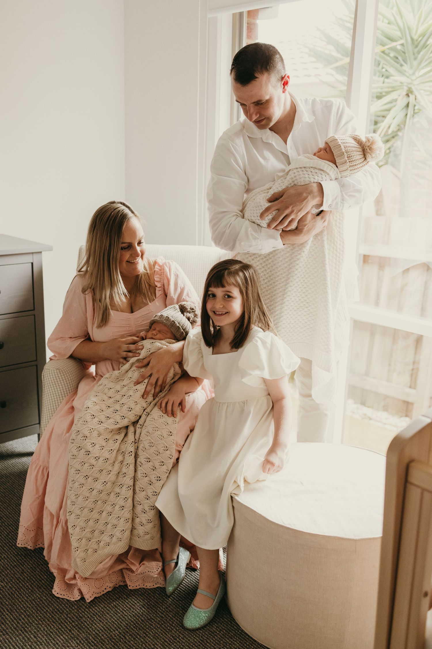 Warm family portrait in modern nursery with natural lighting and minimal decor.