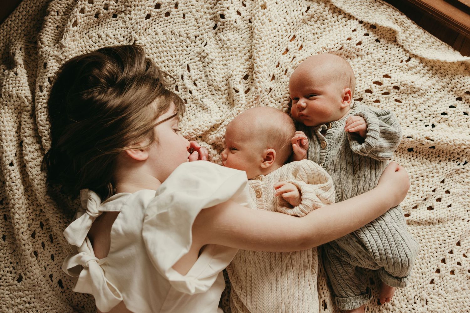 Intimate family moment captured on a textured blanket in warm tones.